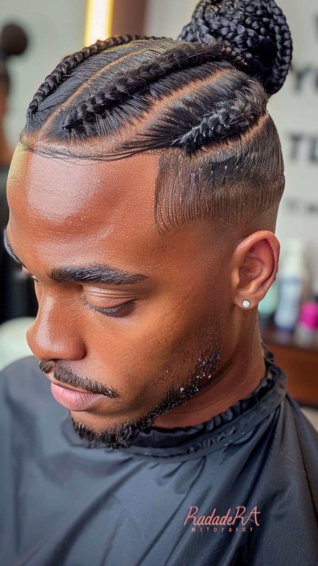 A black man wearing a braided bun hairstyle.